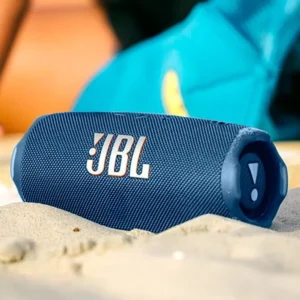 Parlante JBL Flip 7 BT Azul resistente al agua sobre arena de playa en entorno exterior