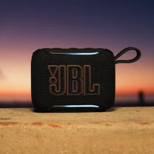 Parlante JBL GO 5 negro con logo naranja sobre piedra frente a un atardecer
