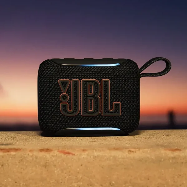 Parlante JBL GO 5 negro con logo naranja sobre piedra frente a un atardecer