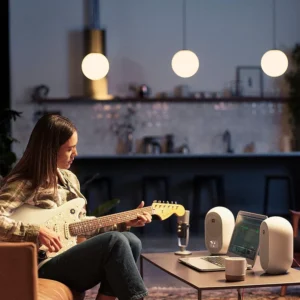 Monitores JBL Pro 104 blancos en estudio casero con mujer tocando guitarra